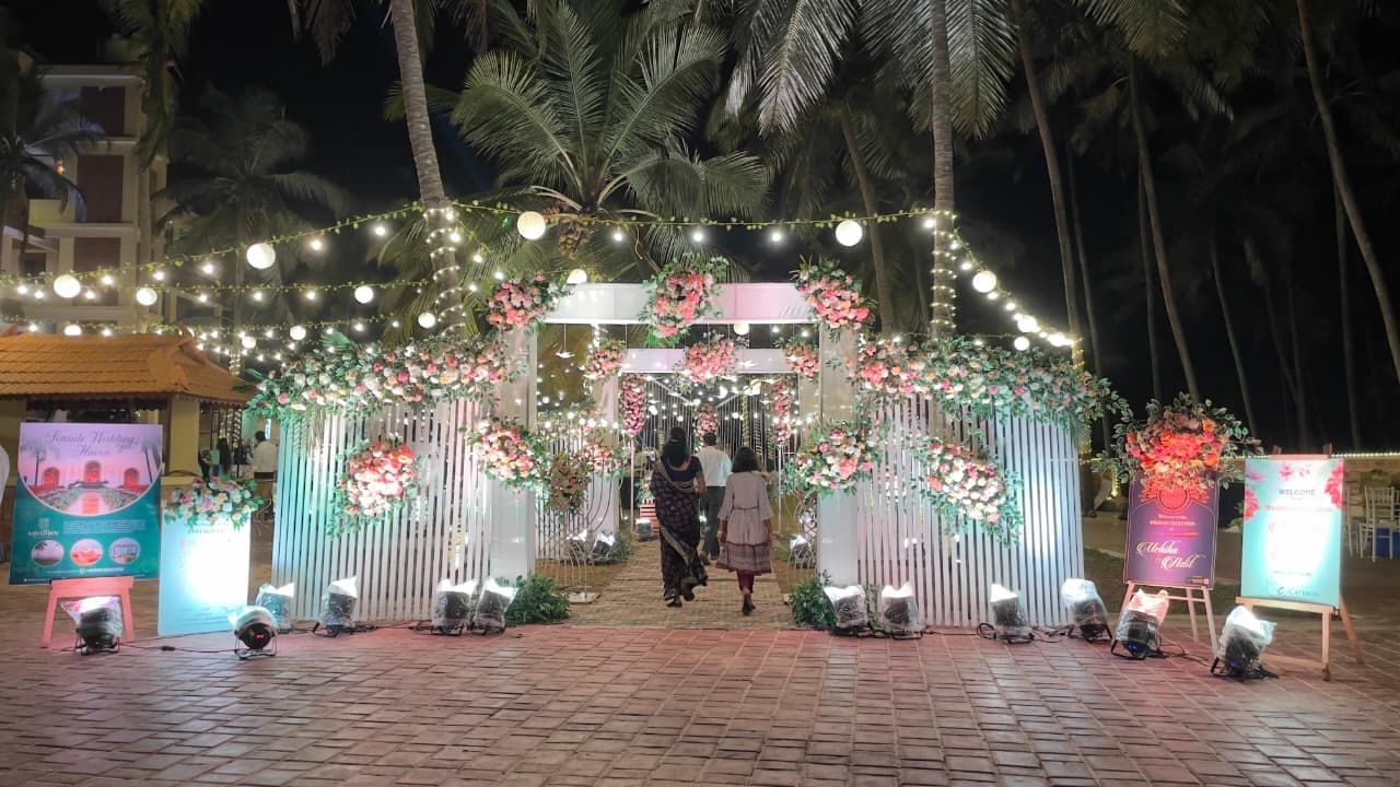 Beautiful wedding entrance gate with floral arch and spotlights by Shanvi Caterers